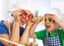 mother and son having fun preparing a meal and holding up bell pepper slices to their eye in a playful manner