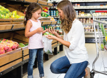 mother and daughter shopping for produce in grocery store