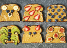 Six slices of peanut butter toast with various fruit toppings